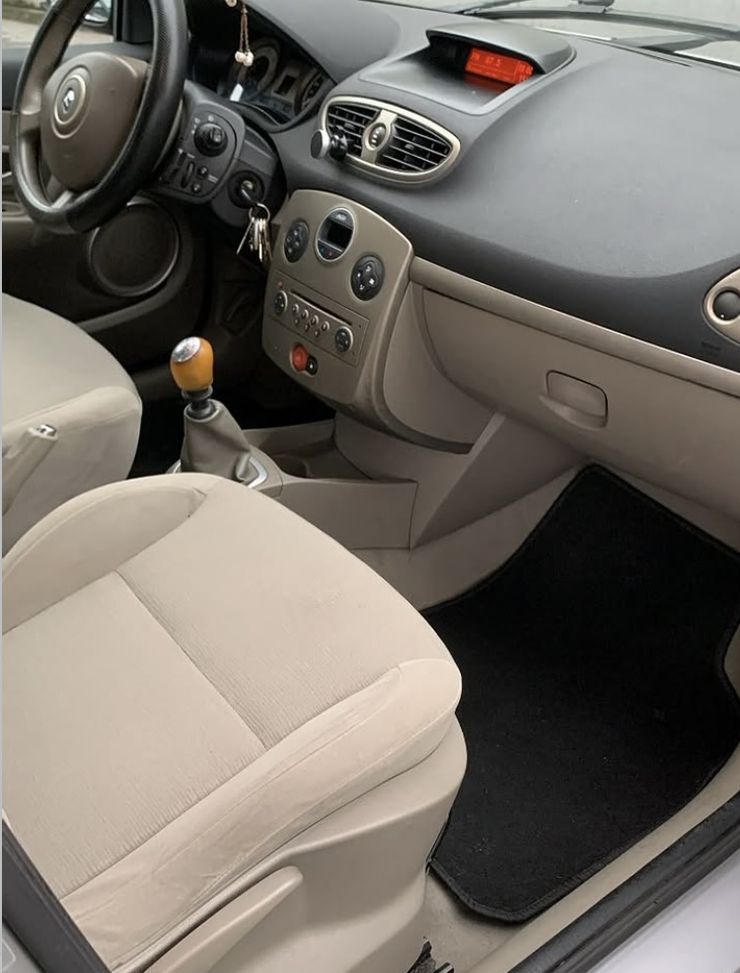 Habitacle d'une Renault Clio après nettoyage : sièges beiges, tableau de bord et tapis de sol propres