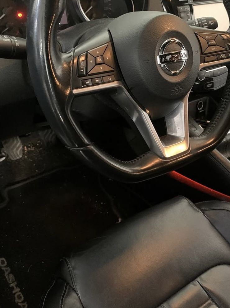 Avant : poste de conduite de Nissan Qashqai avec des débris sur le tapis de sol